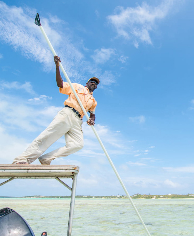 A bonefishing guide poles a skiff in the Bahamas.
